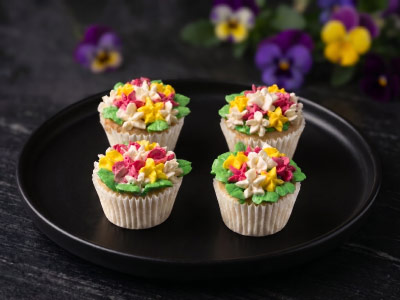 cupcake-fleur-traiteur Mini-cupcakes garnis de glaçage crémeux poché en forme de bouquets de fleurs colorées pour une décoration de buffet traiteur originale.