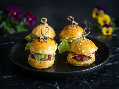 mini-burger-boeuf-traiteur-2 Plateau de mini-burgers au bœuf garnis de salade et présentés dans un pain brioché artisanal pour un buffet dînatoire gourmand.